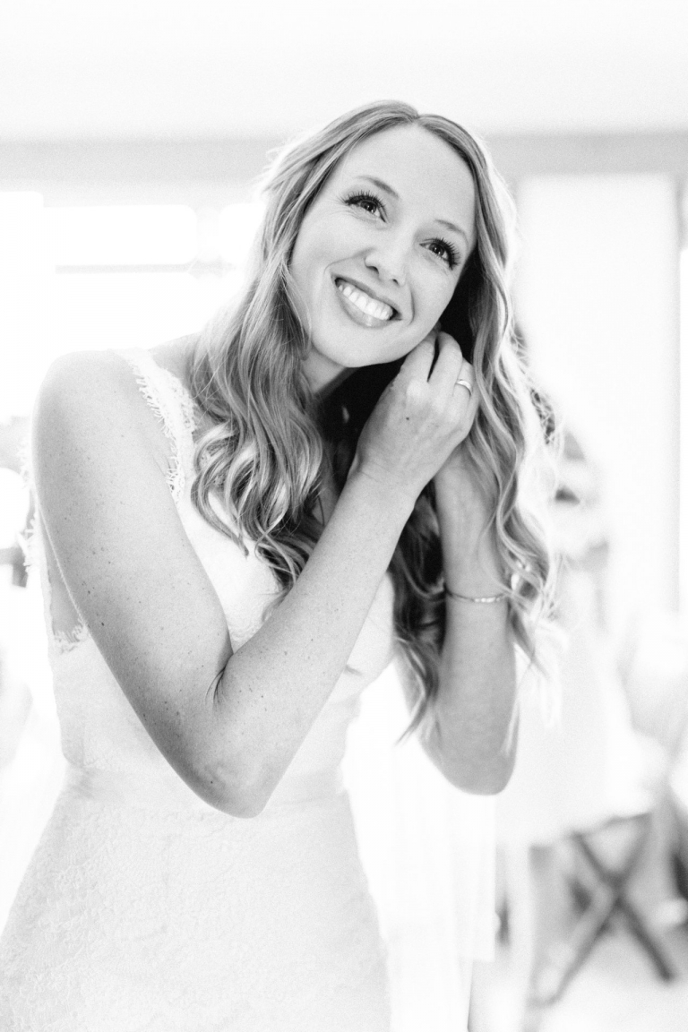 Photo of a bride putting on her earrings