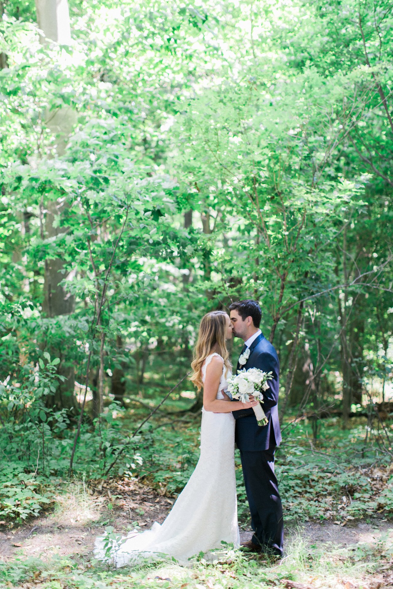 Bride and groom kissing in the woods in Frankfort, Michigan