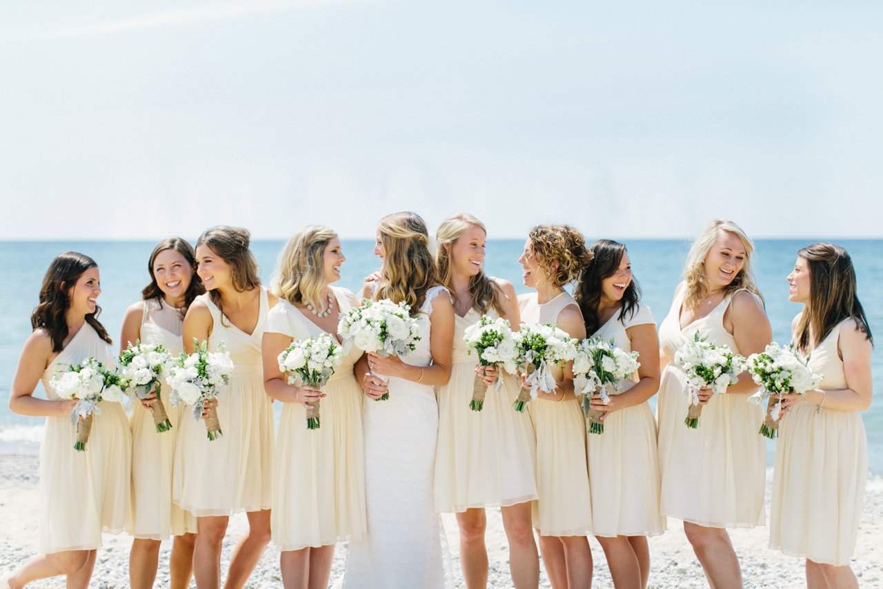 Bridesmaids in J.Crew light yellow dresses smiling at the bride along Lake Michigan