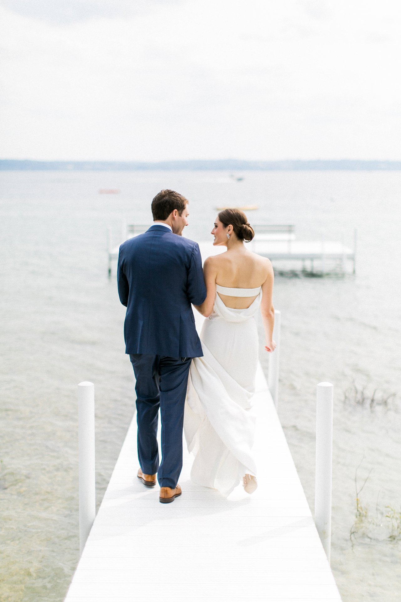 Bride and groom walking down a dock together