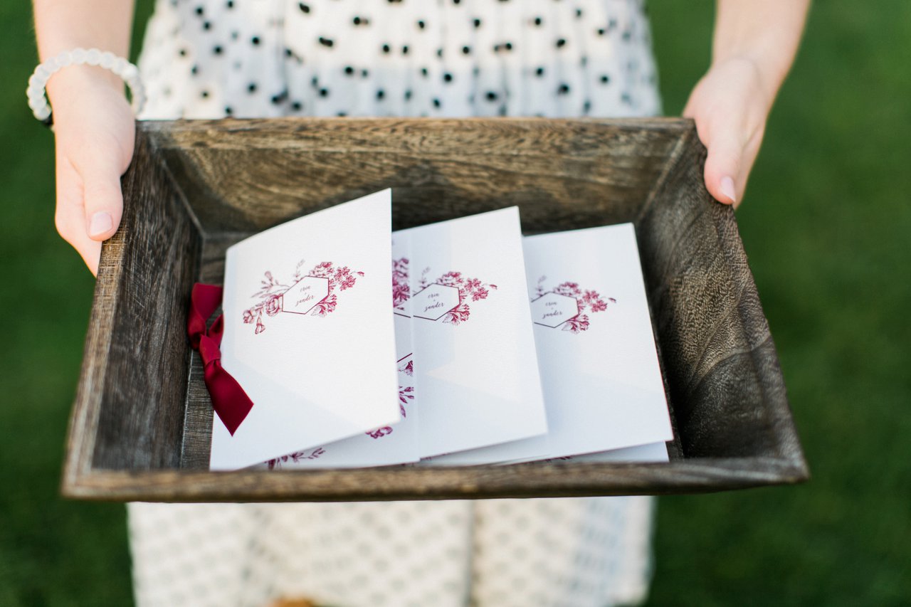 This is a photo of wedding programs in a wooden tray. 