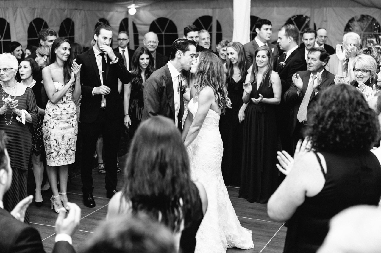 This is a photo of a bride and groom kissing while dancing at their wedding reception. 