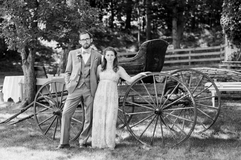 This is a photo of a bride and groom in front of an old wagon in Charlevoix, Michigan.