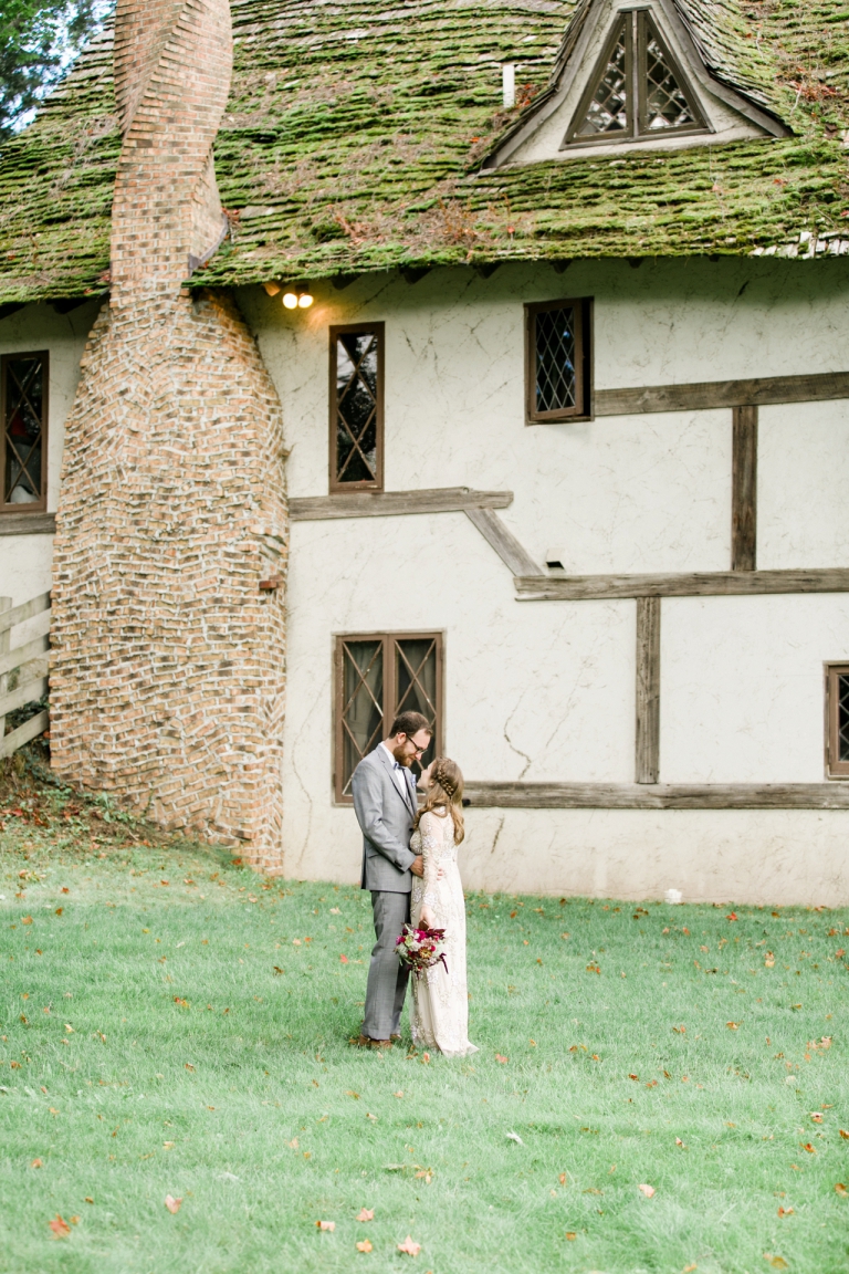 This is a photo of a bride and groom standing in front of an old cottage in Michigan. 