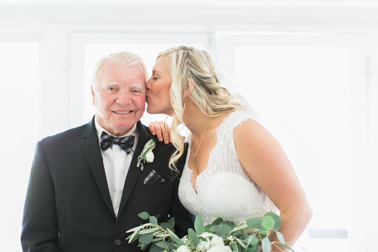 This is a photo of a bride kissing her dad on the cheek 