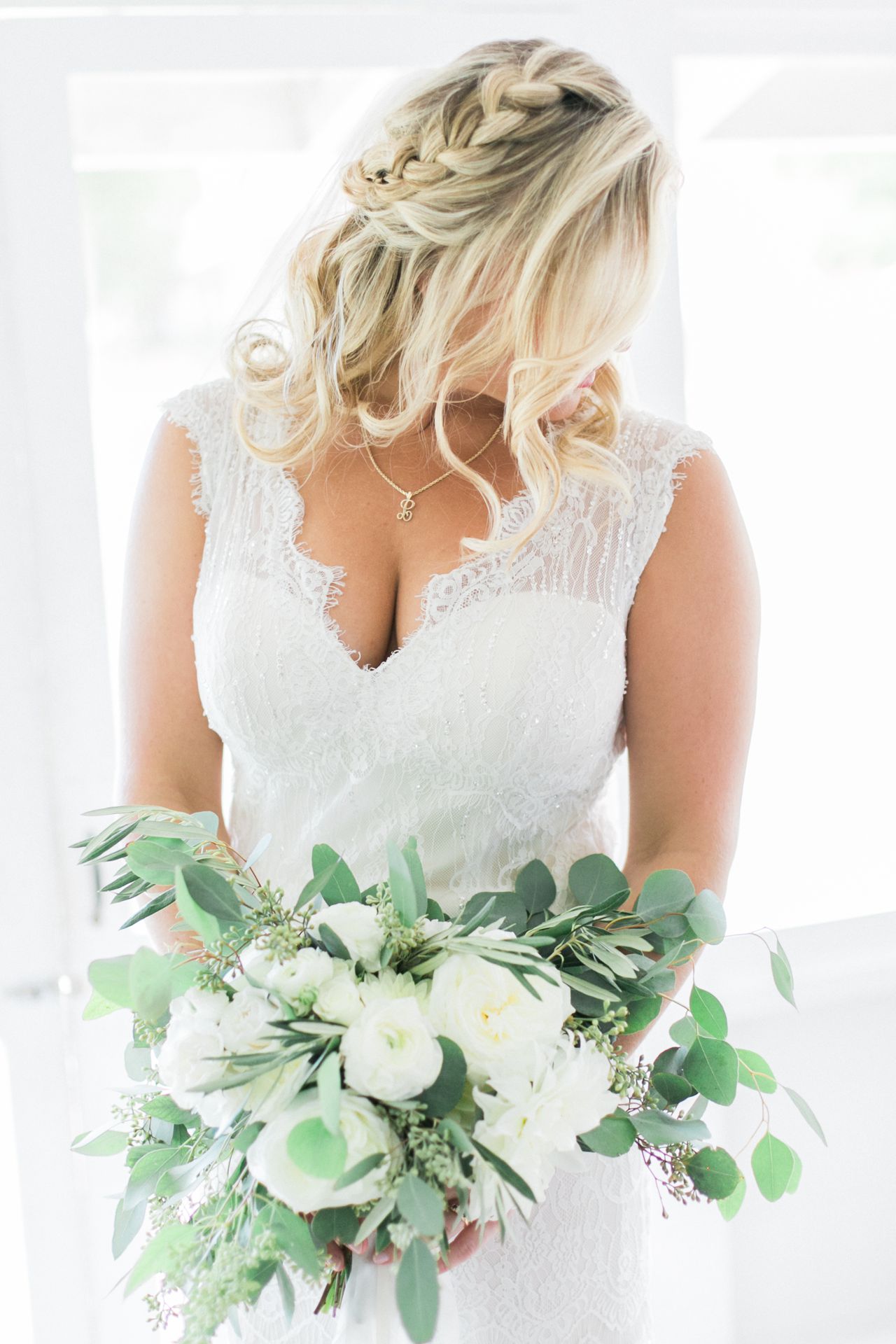 This is a portrait of a bride holding her bouquet looking to the left to show off her braided hair