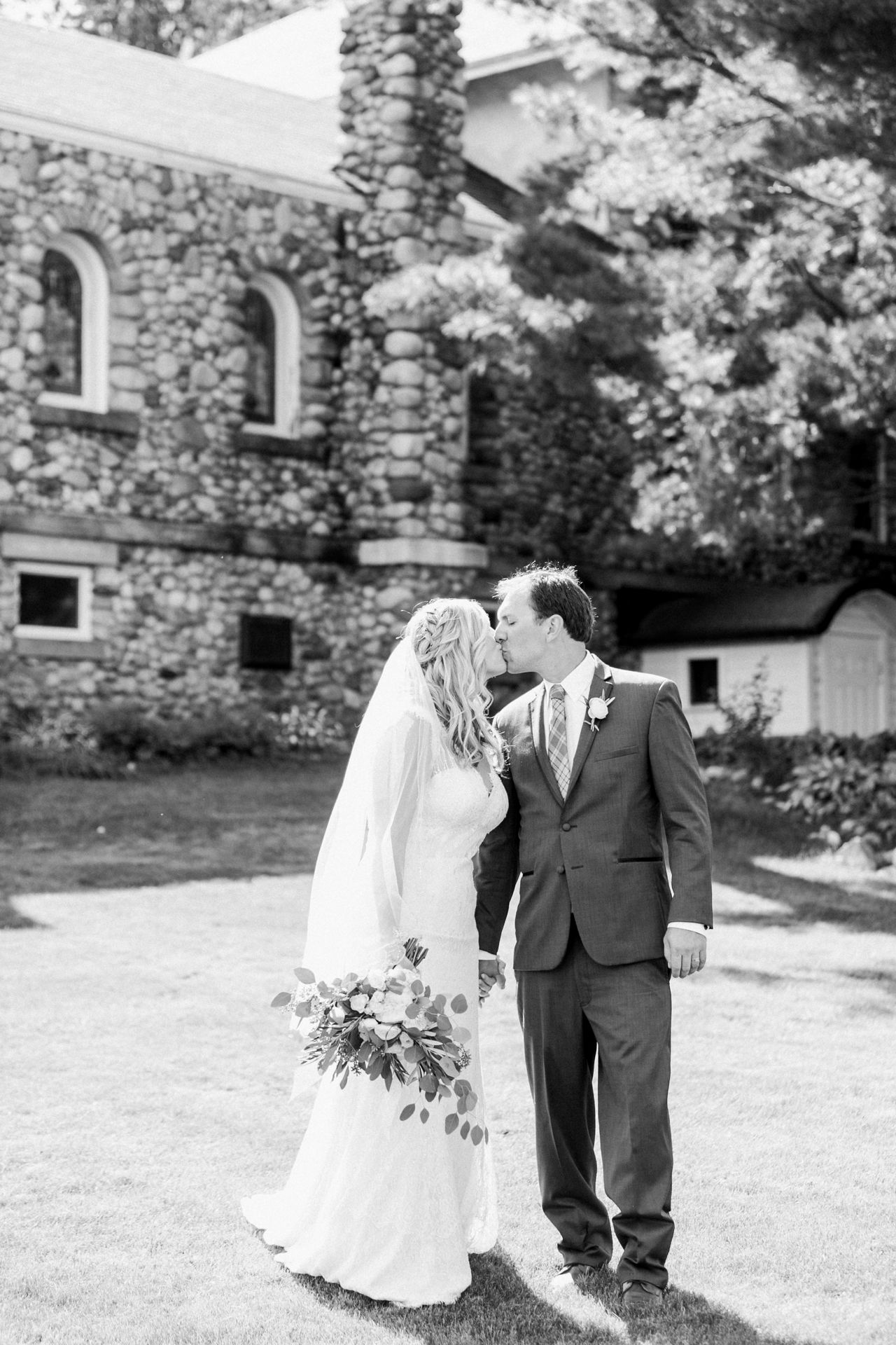 This is a bride and groom kissing outside a church in Lake Leelanau