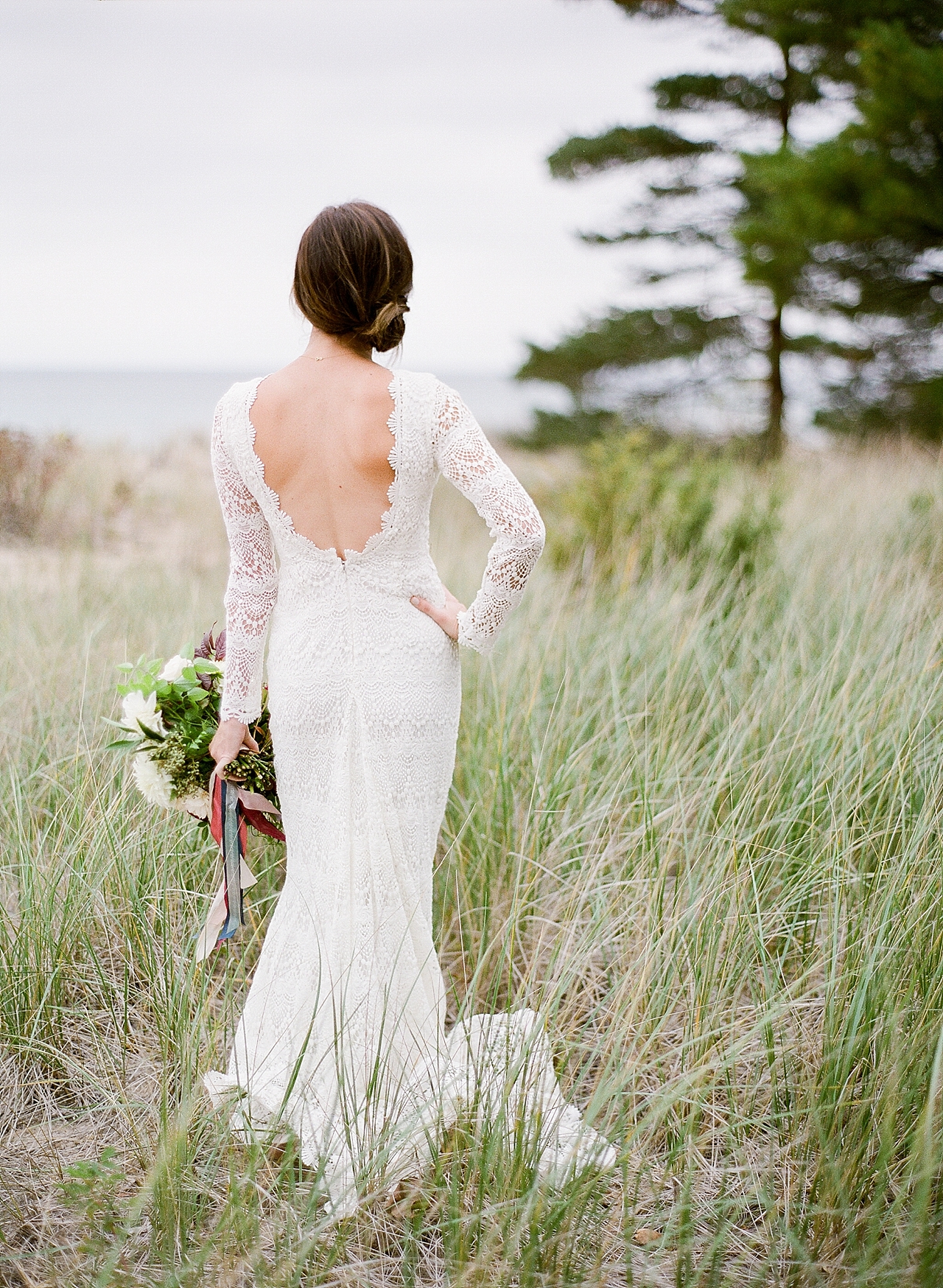 A bride with her hand on her hip looking out at the lake