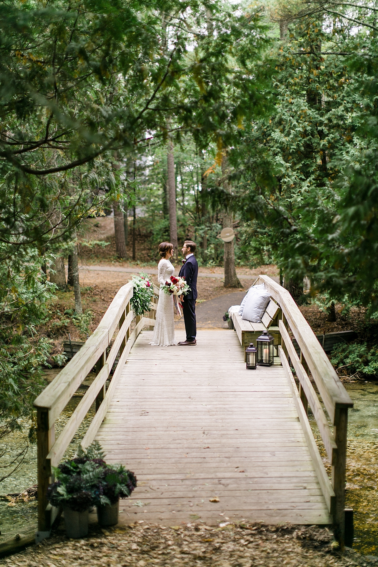 A bride and groom's first look on a wooden bridge in the woods at The Leelanau School in Glen Arbor, Michigan