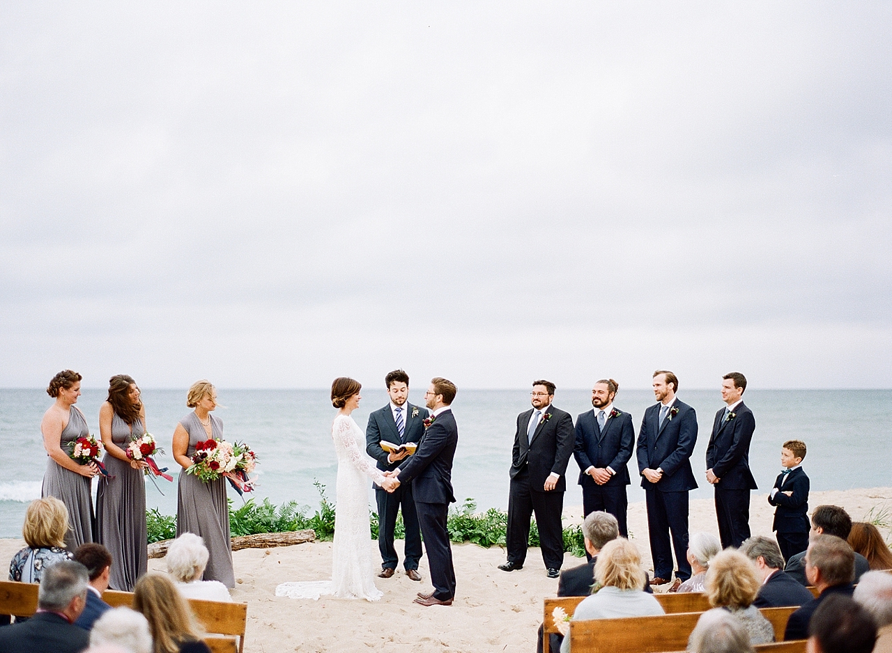 A bride and groom saying their vows at their wedding ceremony with Lake Michigan in the background