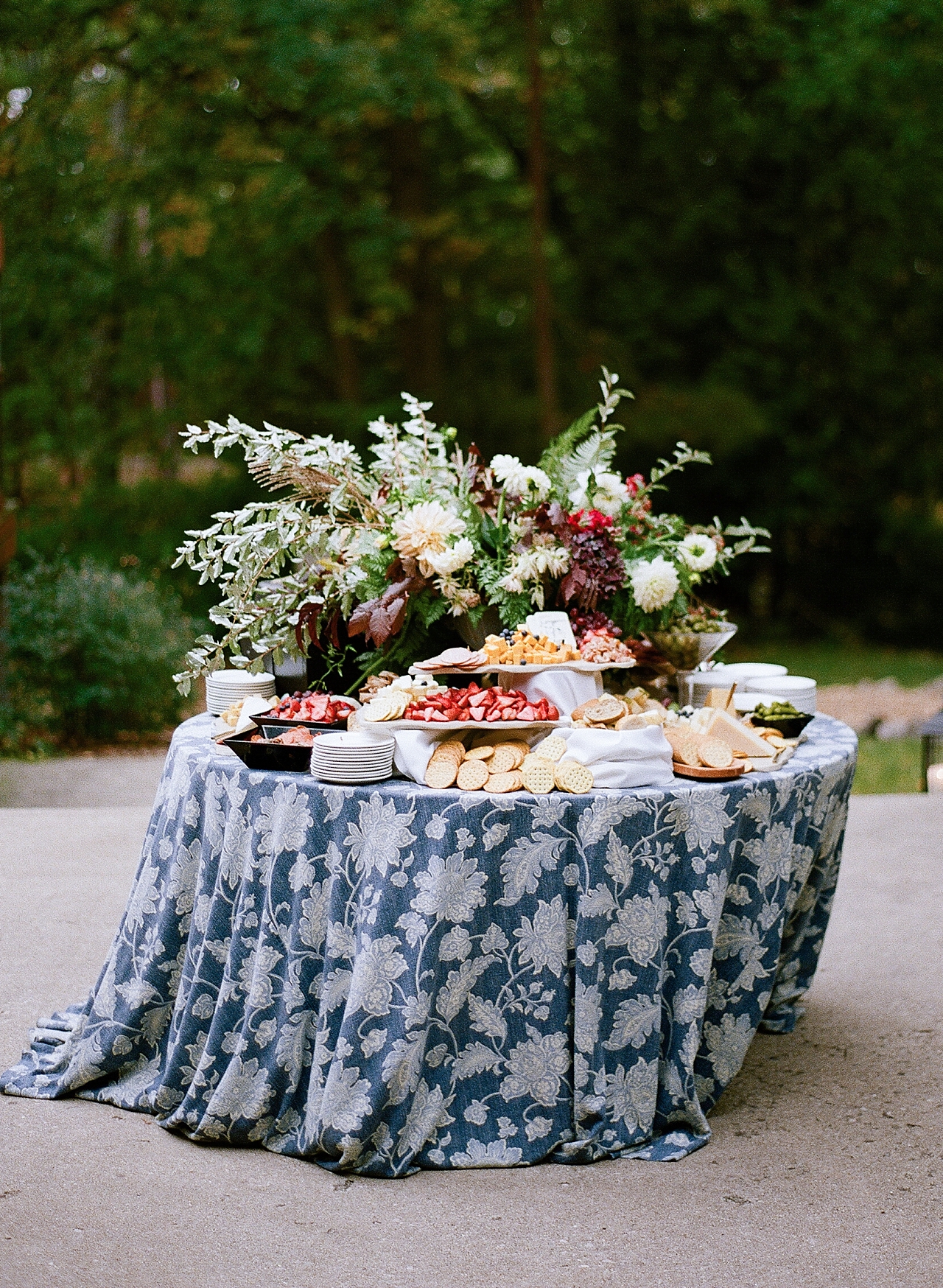 A cocktail hour table with a blue floral linen and appetizers 