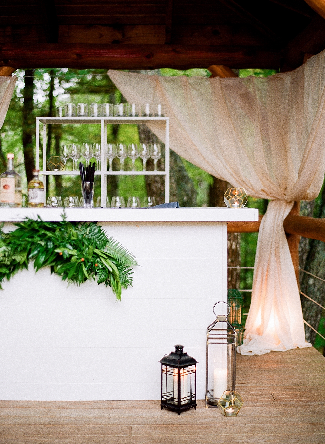 A cocktail bar with candles and greenery inside of the reception tent in Glen Arbor, Michigan