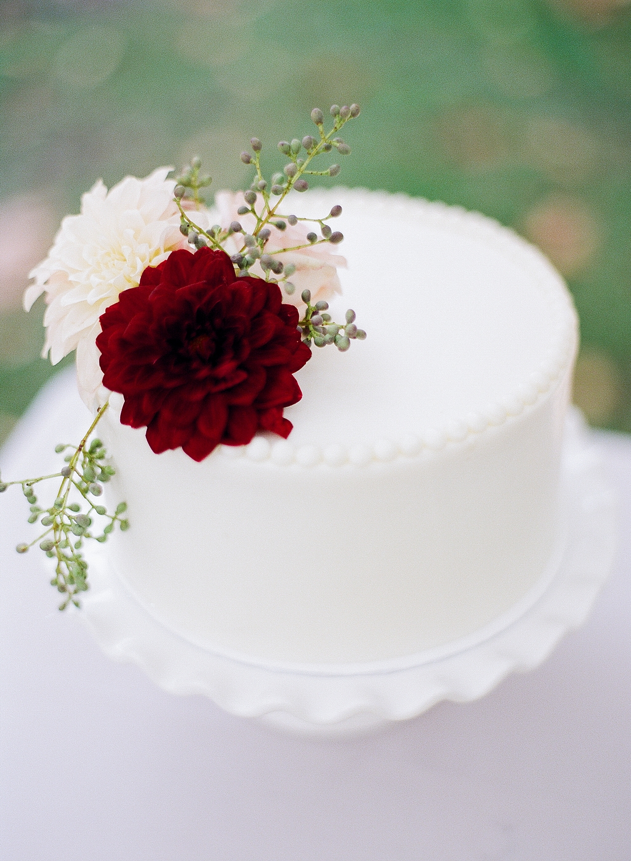 A single layer wedding cake with a burgundy flower on the top at The Leelanau School in Glen Arbor, Michigan