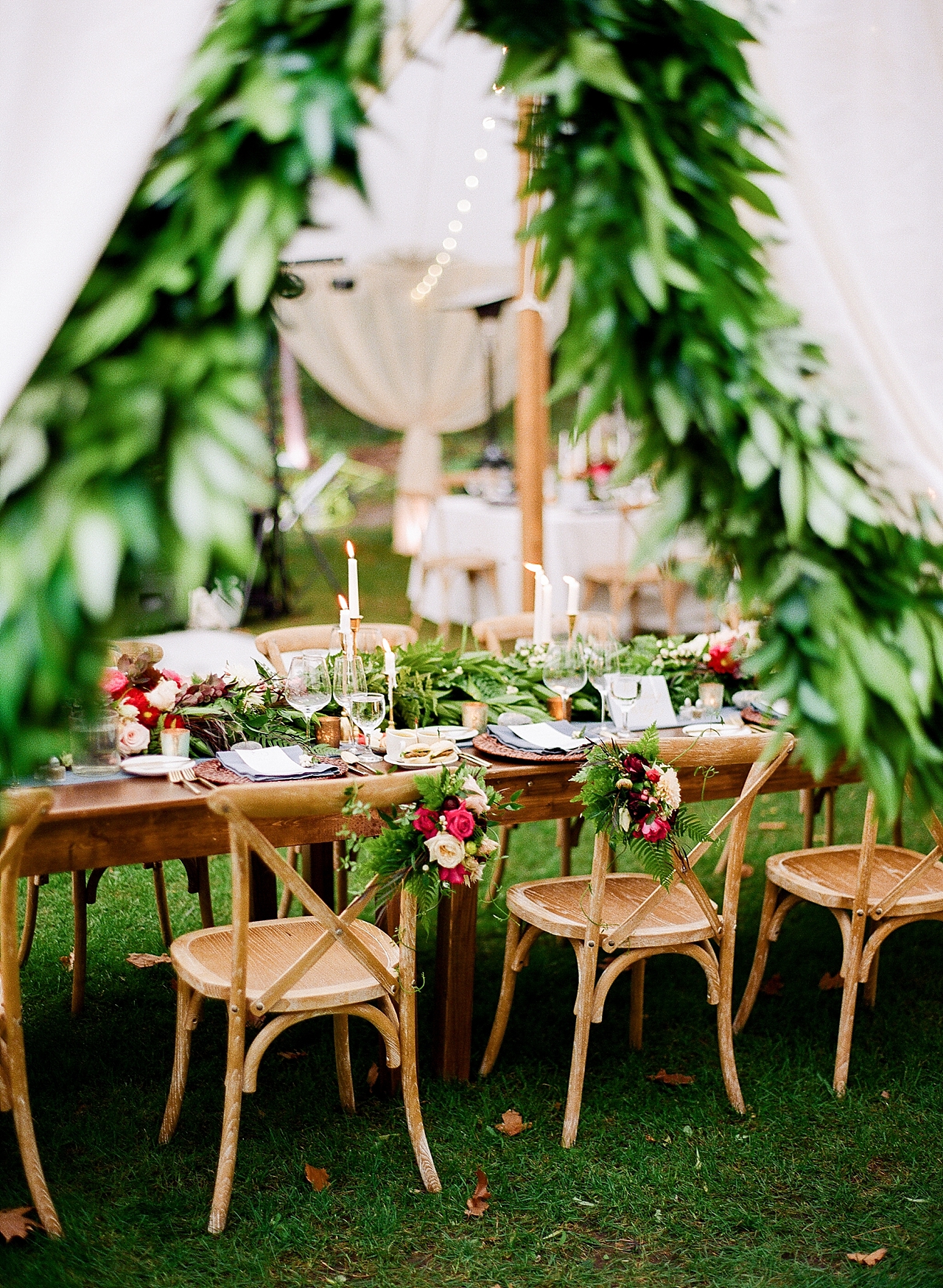 The reception tent with wooden chairs, greenery, and burgundy flowers at The Leelanau School in Glen Arbor, Michigan
