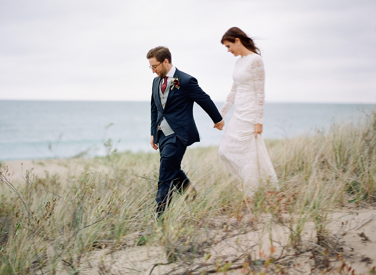 A bride and groom walking through Sleeping Bear Dunes in Glen Arbor, Michigan