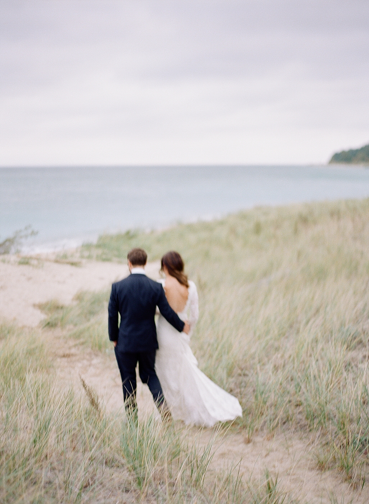 Bride and groom walking through dunes at The Leelanau School in Glen Arbor