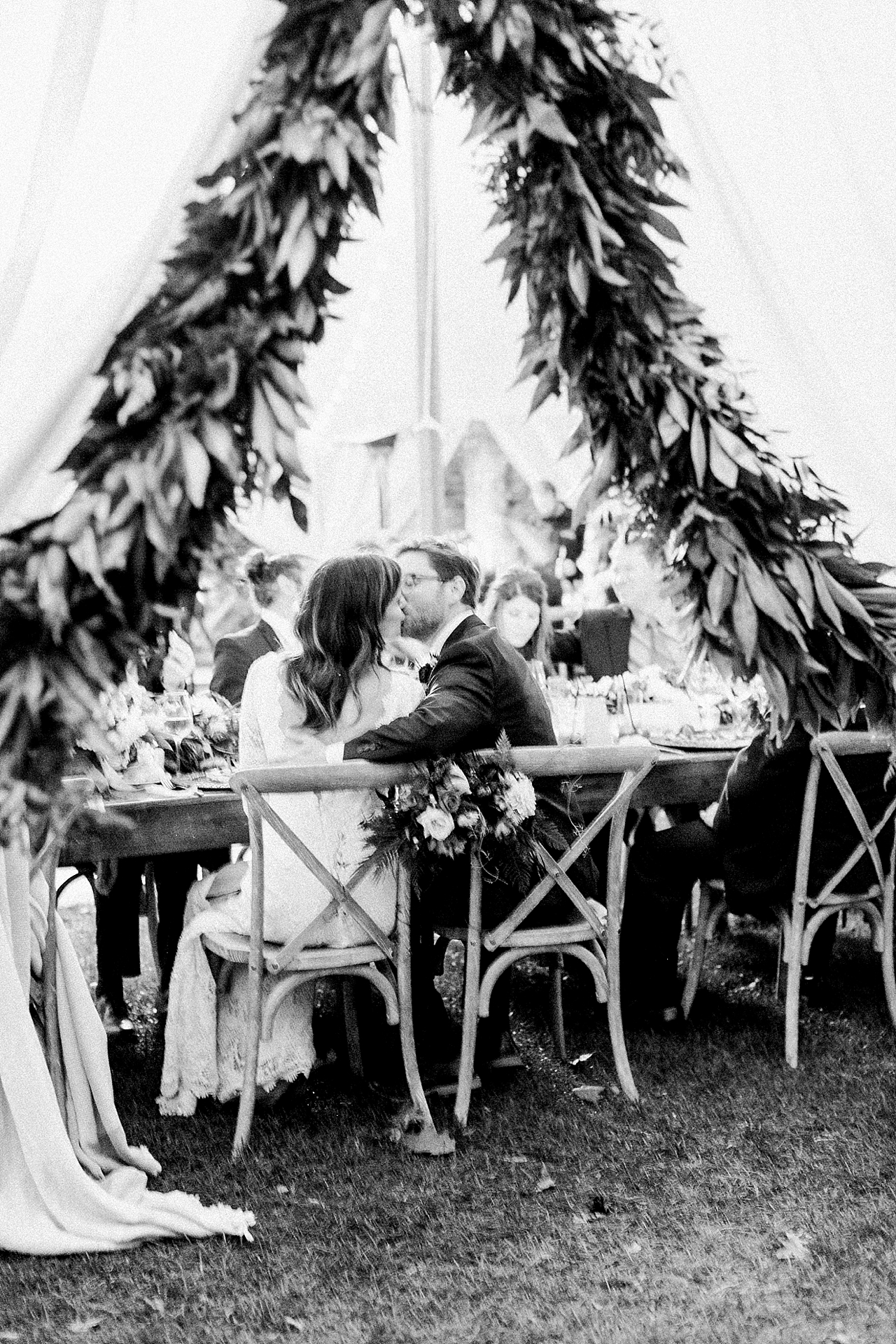 Bride and groom kissing while sitting at the reception