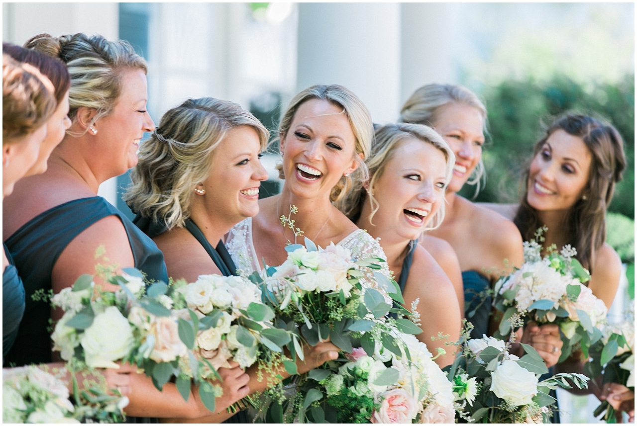 A bride looking at her bridesmaids dressed in navy blue and laughing