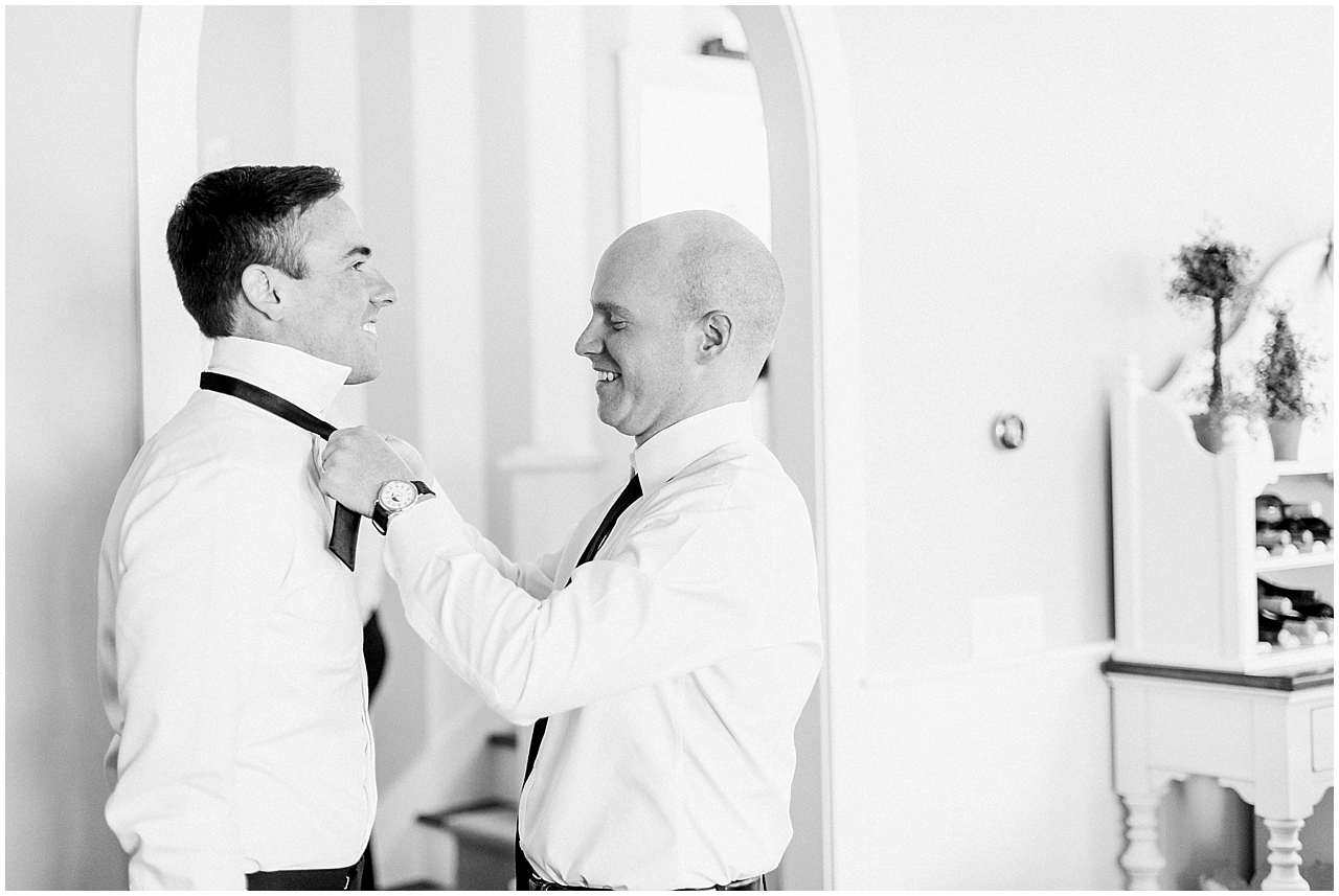 A groomsmen helping the groom put on his tie in Northern Michigan on Walloon Lake
