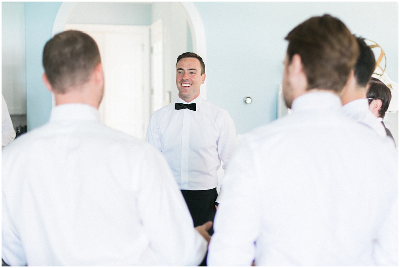 The groom smiling while chatting with his groomsmen on Walloon Lake