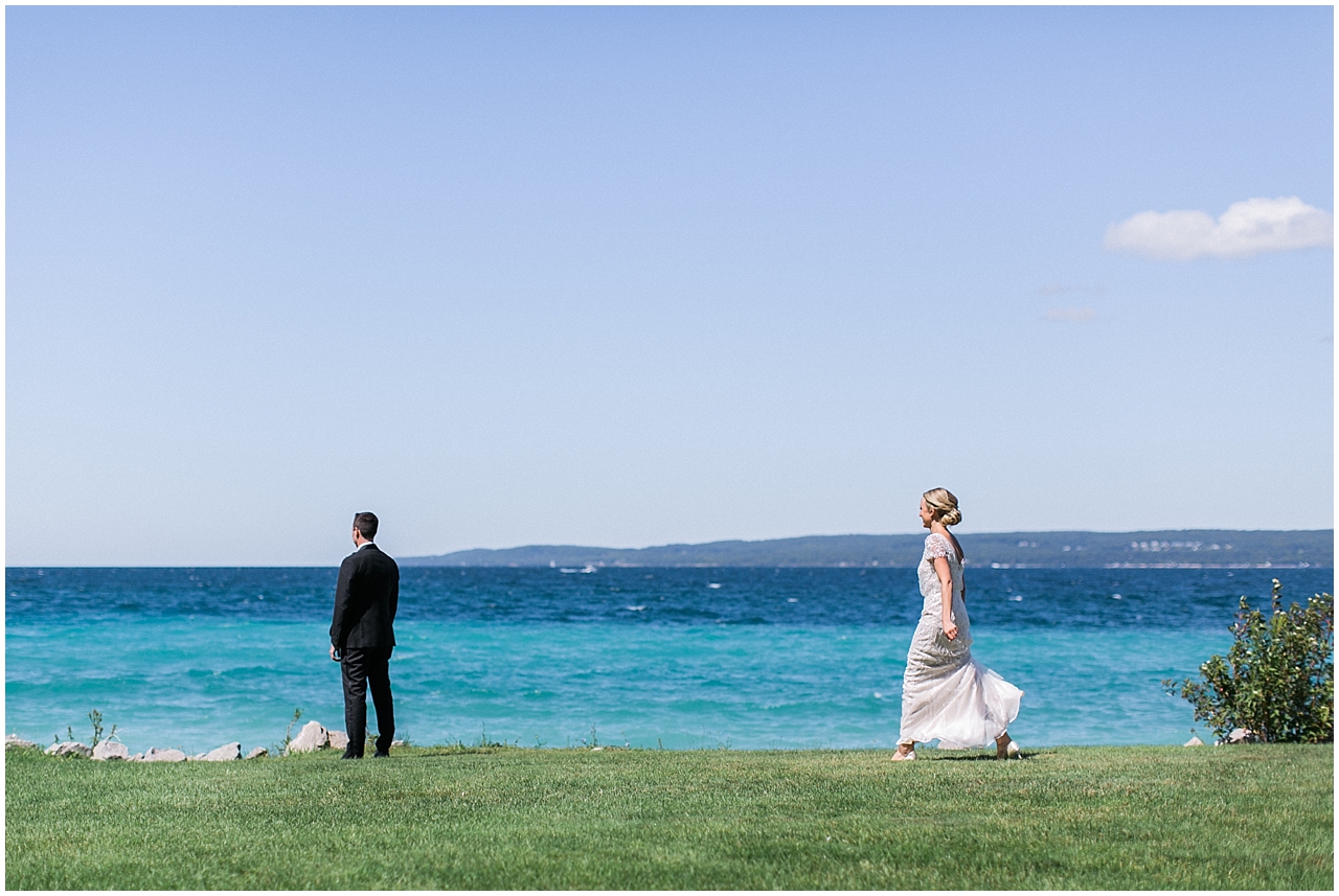 Bride walking towards the groom for their first look along the water in Bay Harbor, Michigan