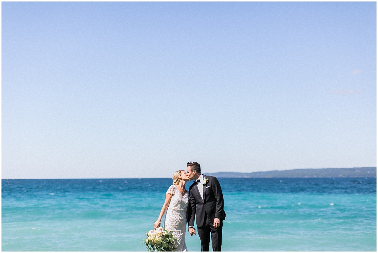 Bride and groom kissing in front of the lake in Bay Harbor, Michigan