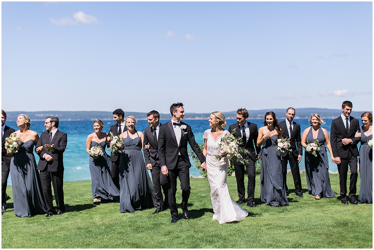 Bride and groom walking with their wedding party in front of the lake in Bay Harbor, Michigan