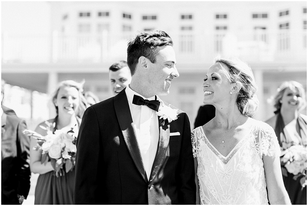 Bride and groom walking and smiling at each other with their wedding party in Bay Harbor, Michigan