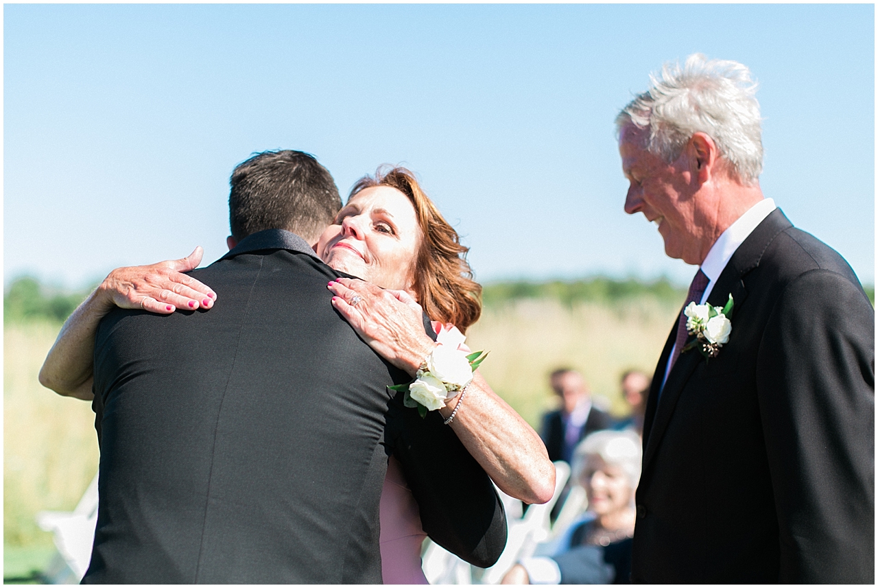 A mother hugging the groom at the ceremony in Charlevoix, Michigan