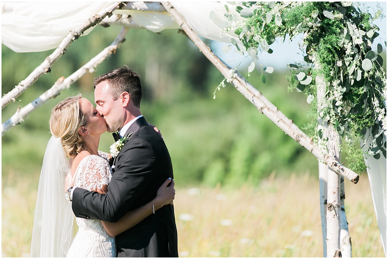 Bride and grooms first kiss during their ceremony at Shanahan's Barn in Charlevoix, Michigan