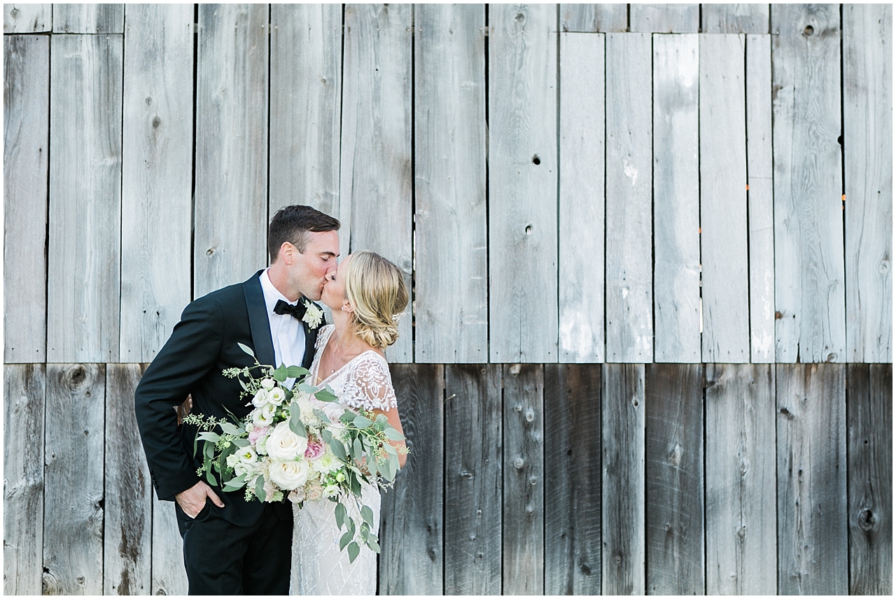Bride and groom kissing in front of Shanahan's Barn in Charlevoix, Michigan
