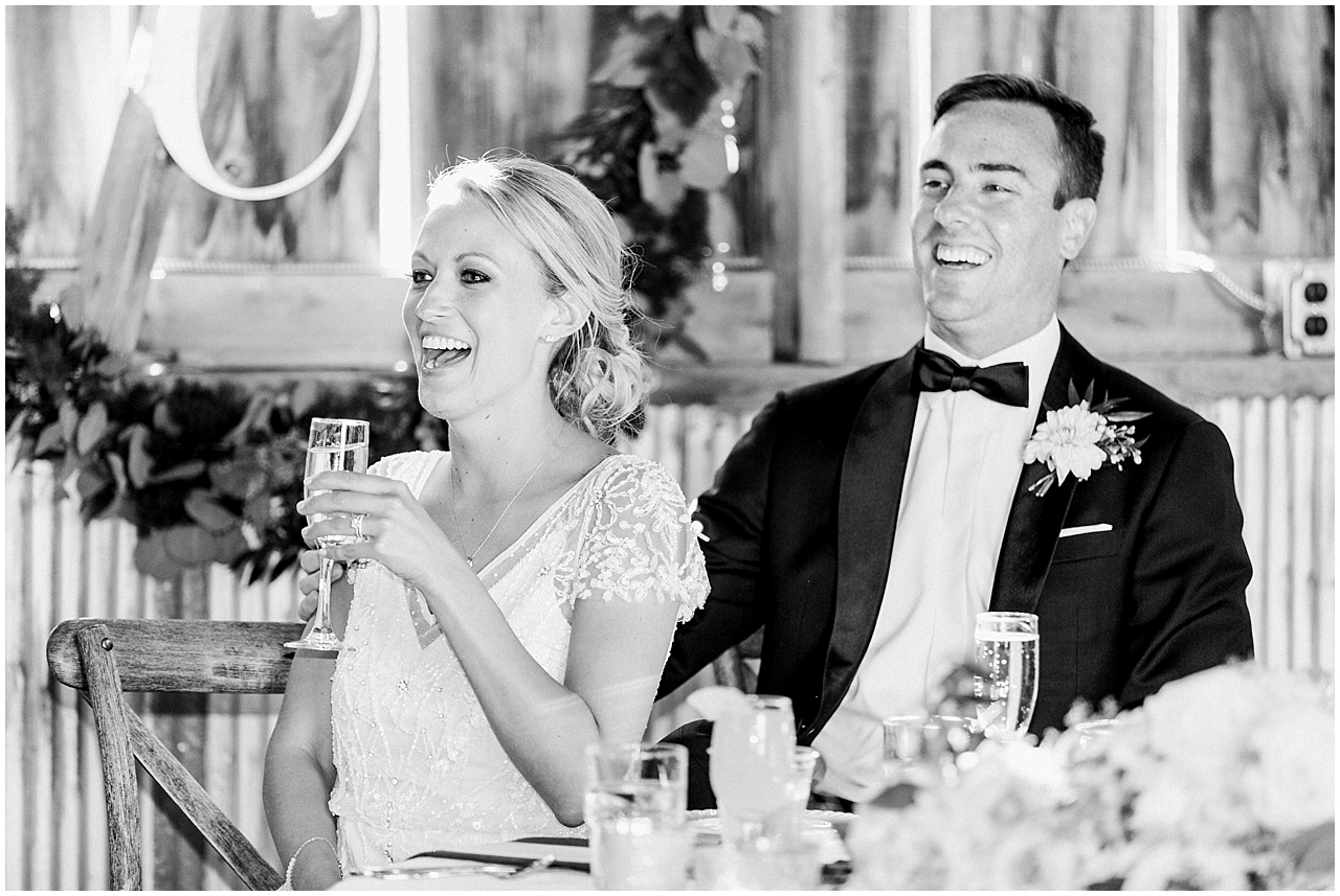The bride and groom laughing during the speeches at the wedding reception at Shanahan's barn in Charlevoix, Michigan