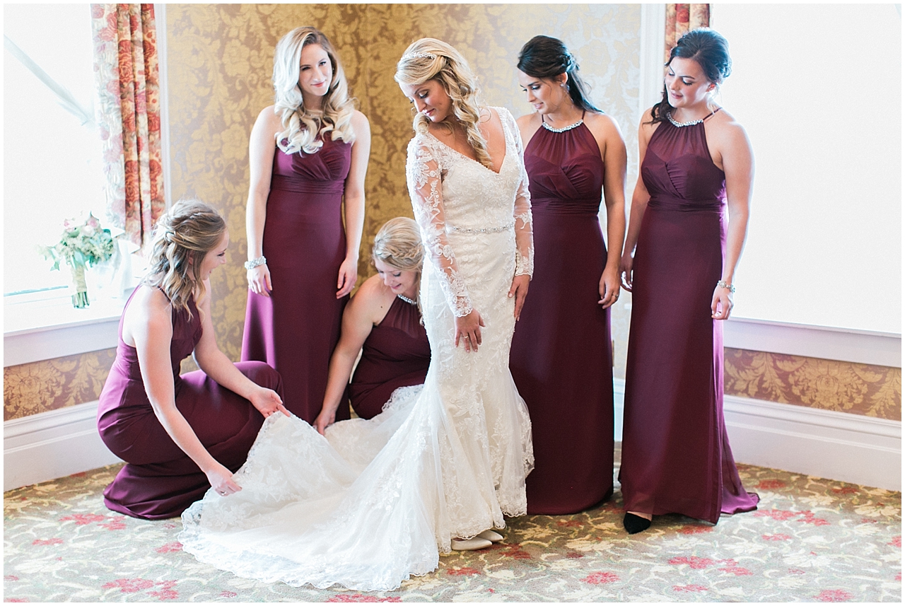 A bride putting on her final wedding attire with the help of her 5 bridesmaids