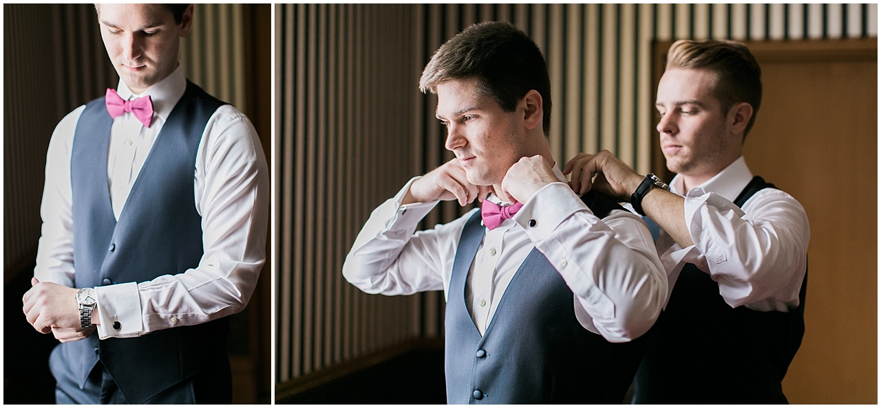 A groom putting on his tie with the help of the best man in the library at Stafford's Perry Hotel