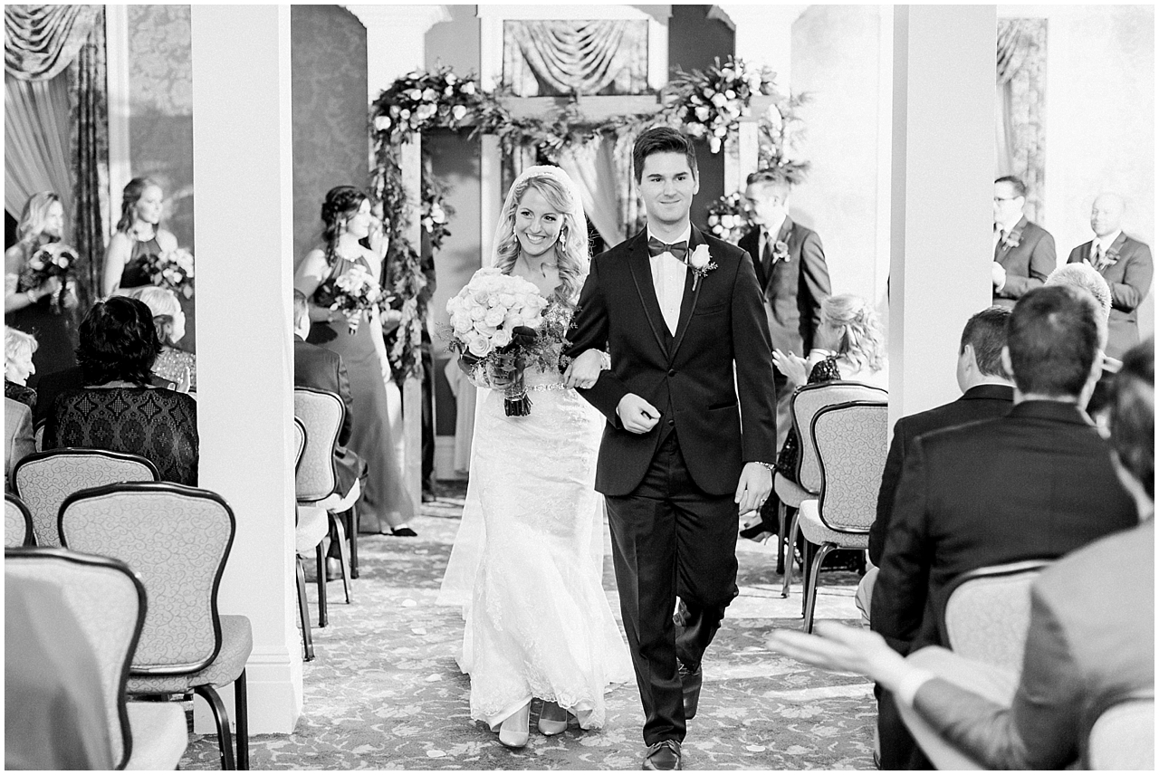 A bride and groom walking down the aisle together after their wedding ceremony at the Stafford's Perry Hotel