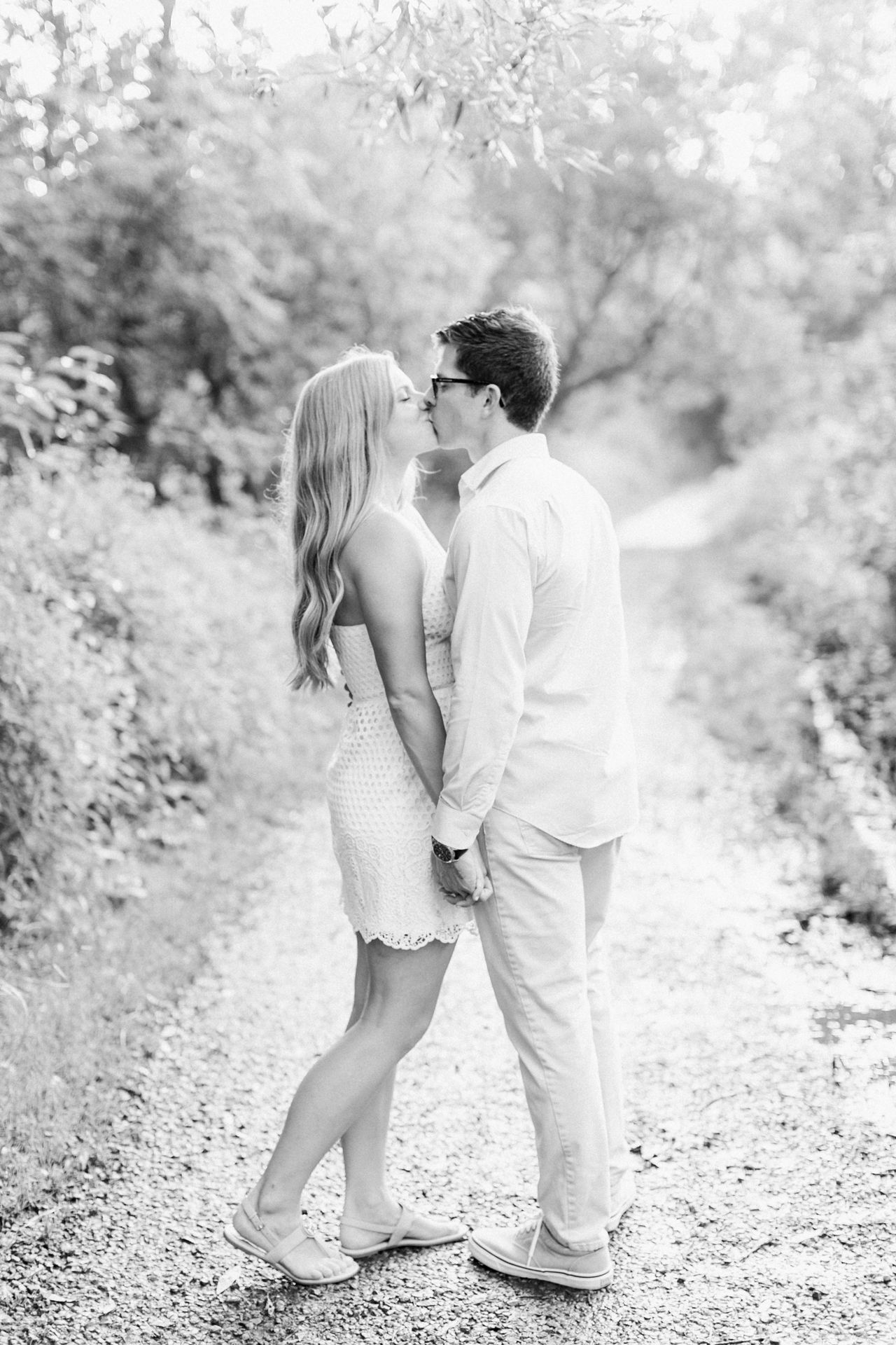 This is an engaged couple kissing on a hiking trail The Village at Grand Traverse Commons in Traverse City, Michigan