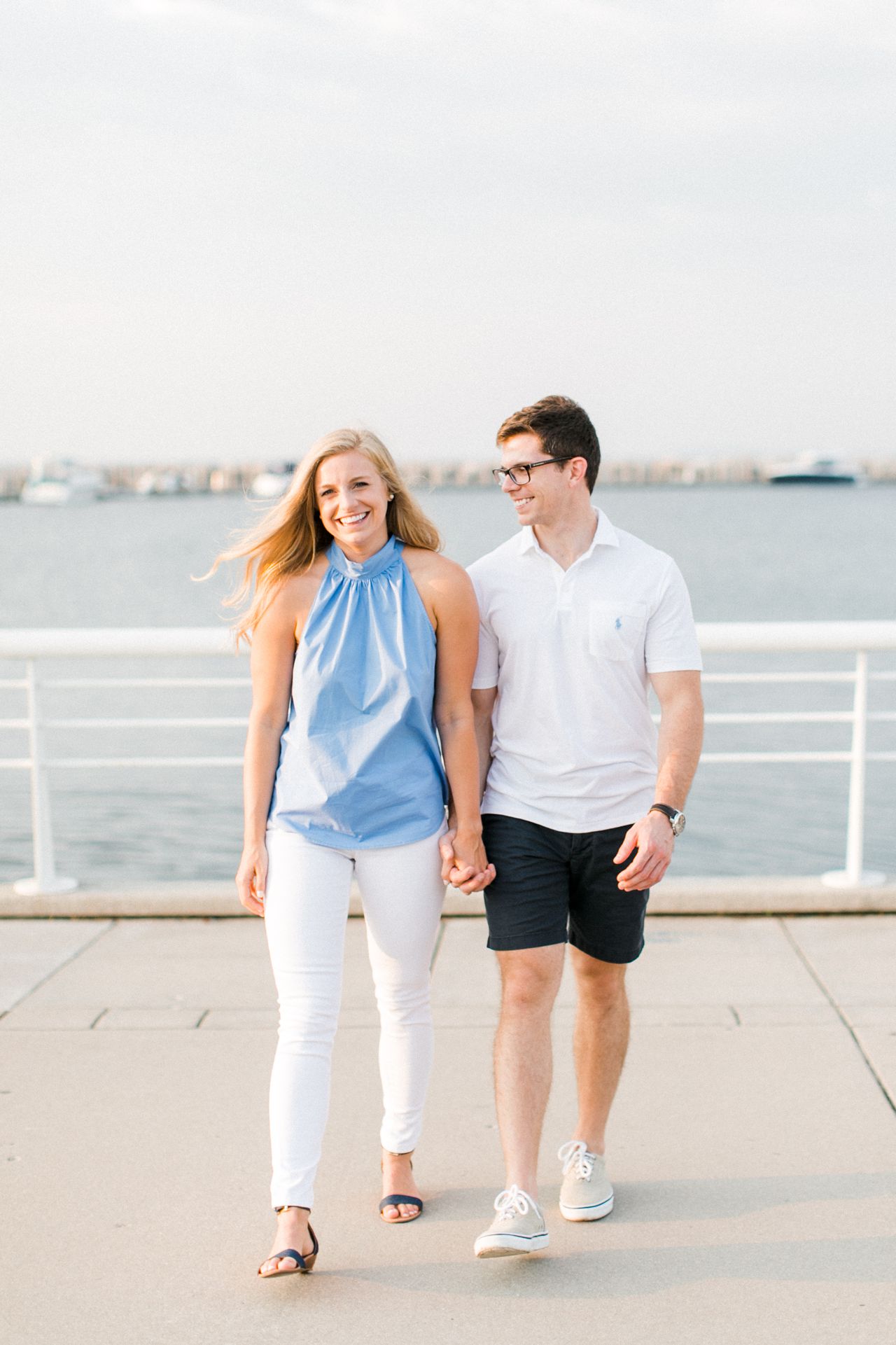 This is an engaged couple walking and laughing at a marina in Traverse City, Michigan