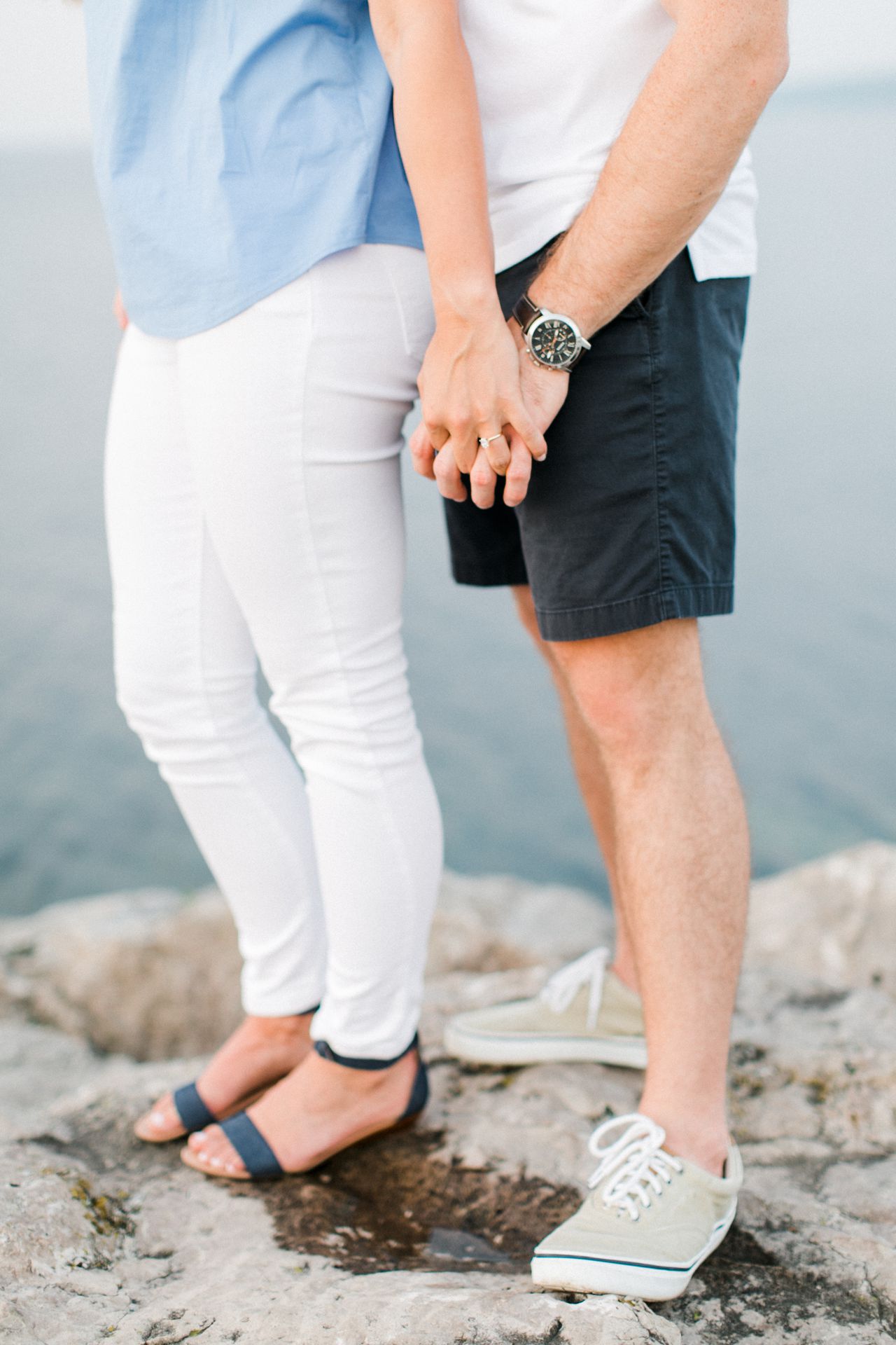 This is an engaged couple holding hands by the lake in Michigan