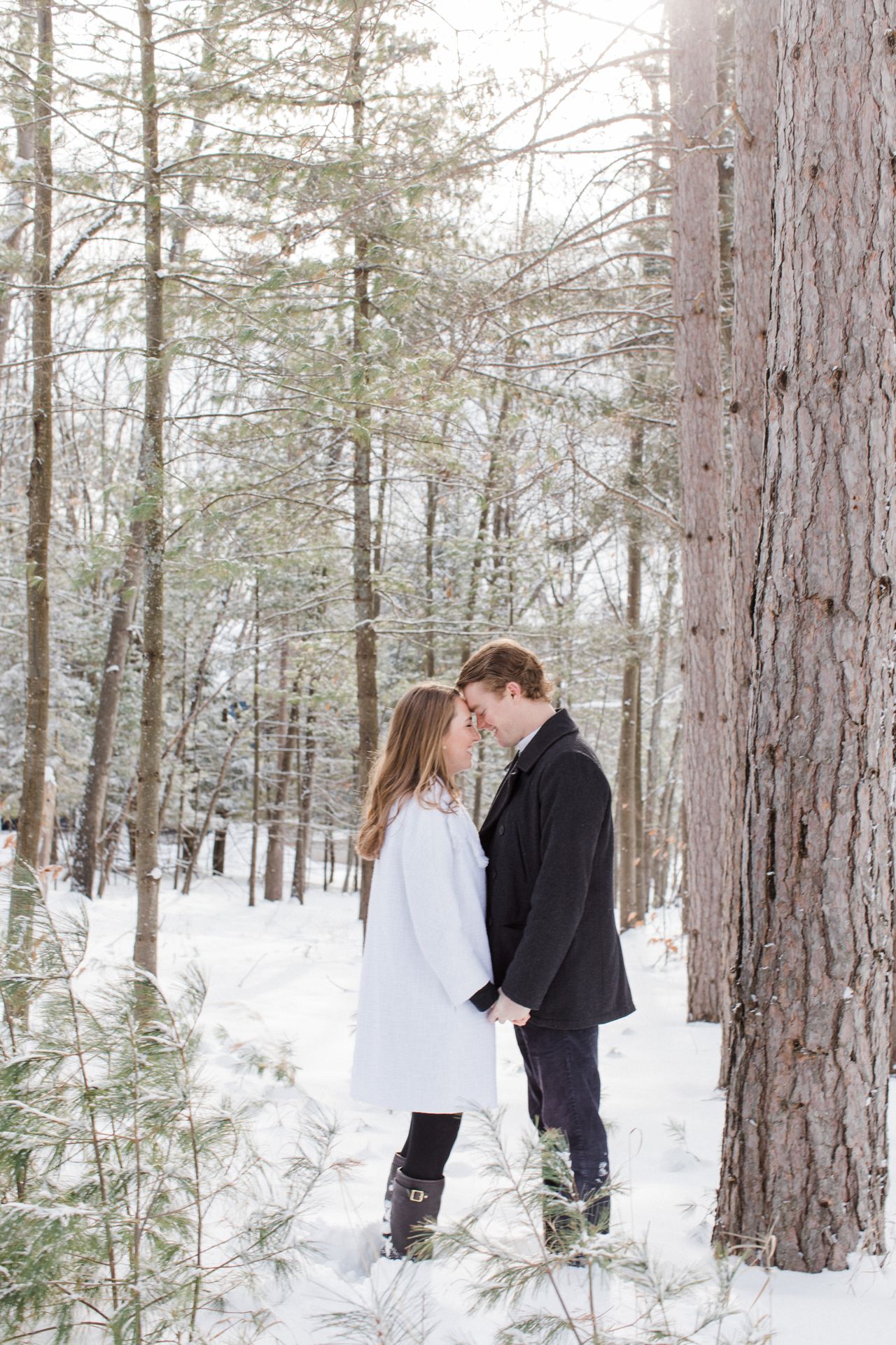This is a couple with their foreheads touching in snowy woods in Harbor Springs, Michigan
