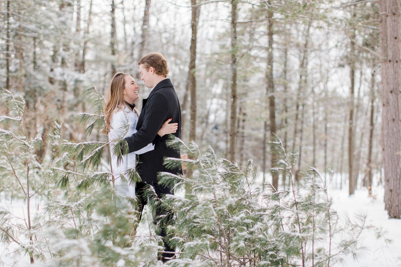 This is a couple laughing while taking engagement photos in the woods in Harbor Springs, Michigan