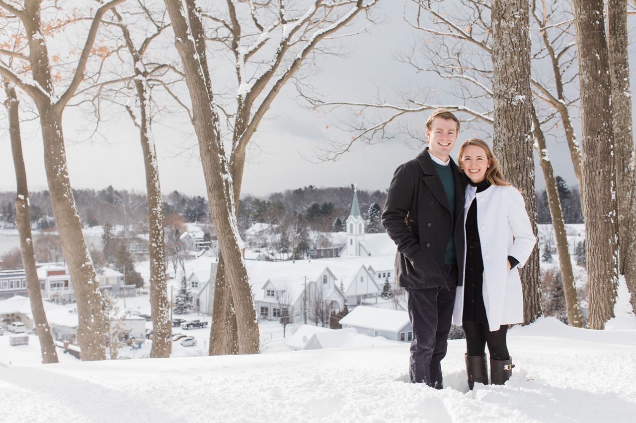 This is a couple smiling while taking photos with Downtown Harbor Springs in the background