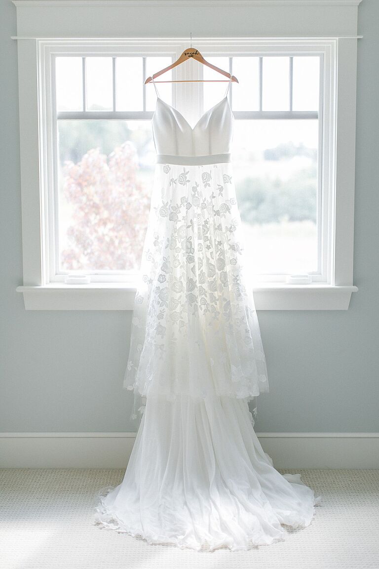 Beautiful lace wedding dress hanging from a window