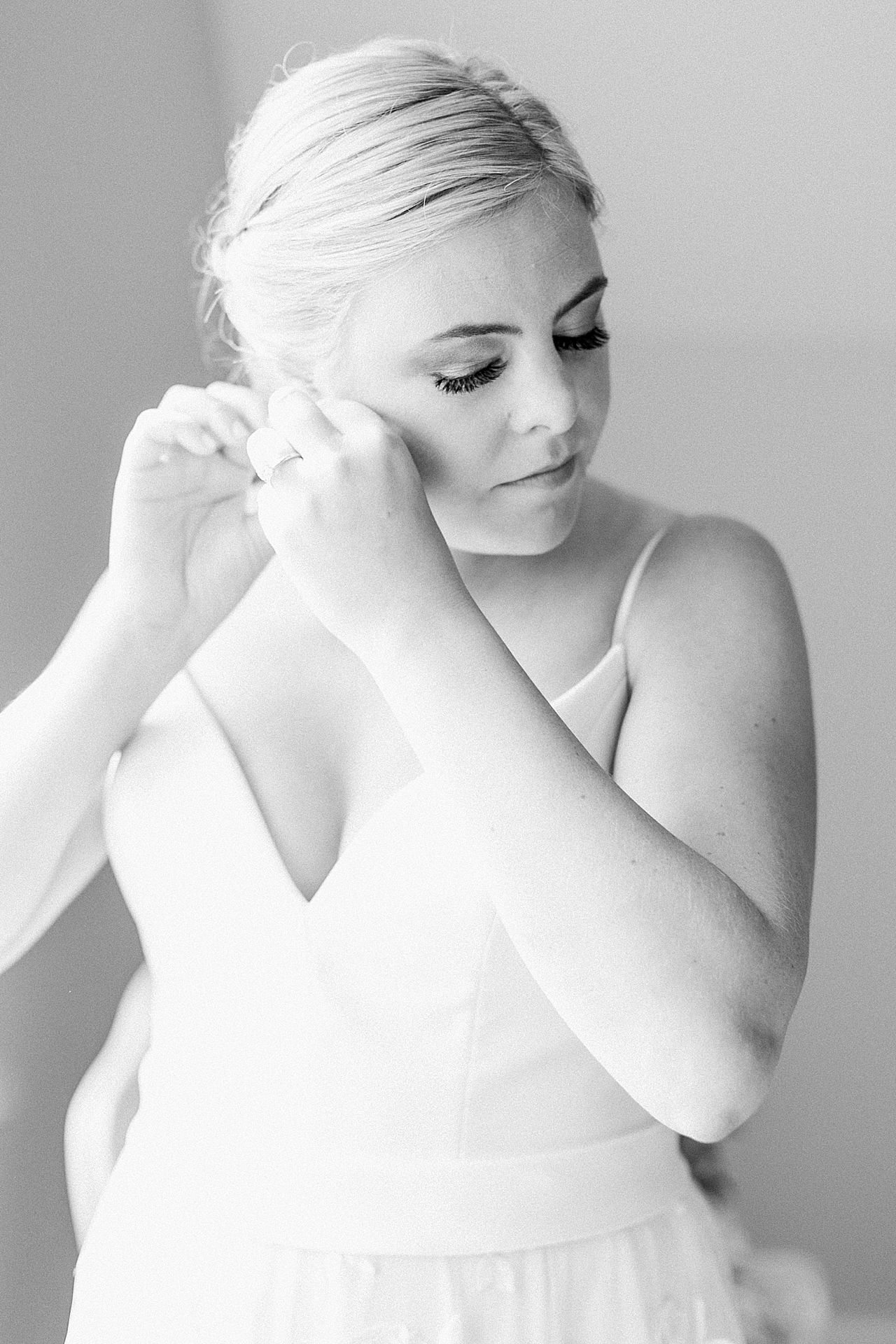 Bride putting her earrings on before her wedding
