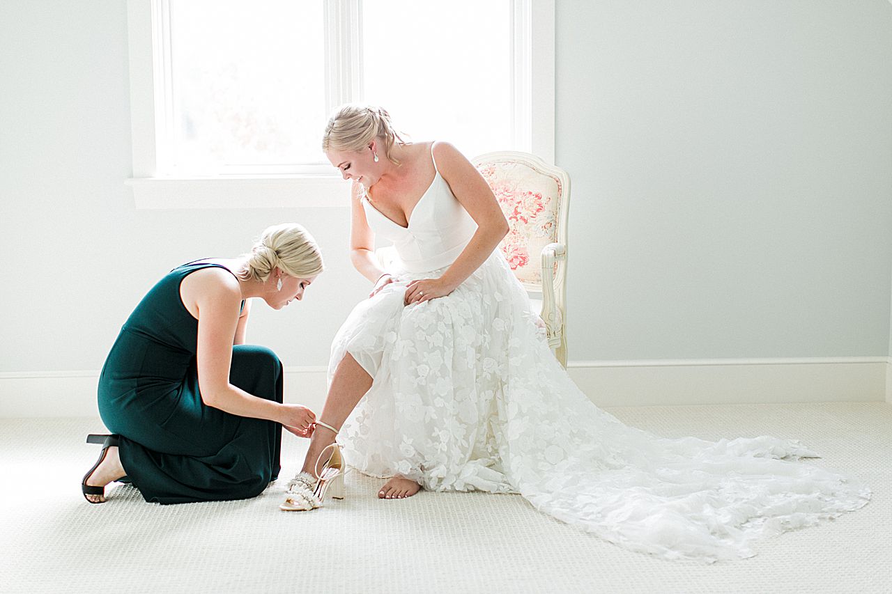Bridesmaid helping the bride put her heels on