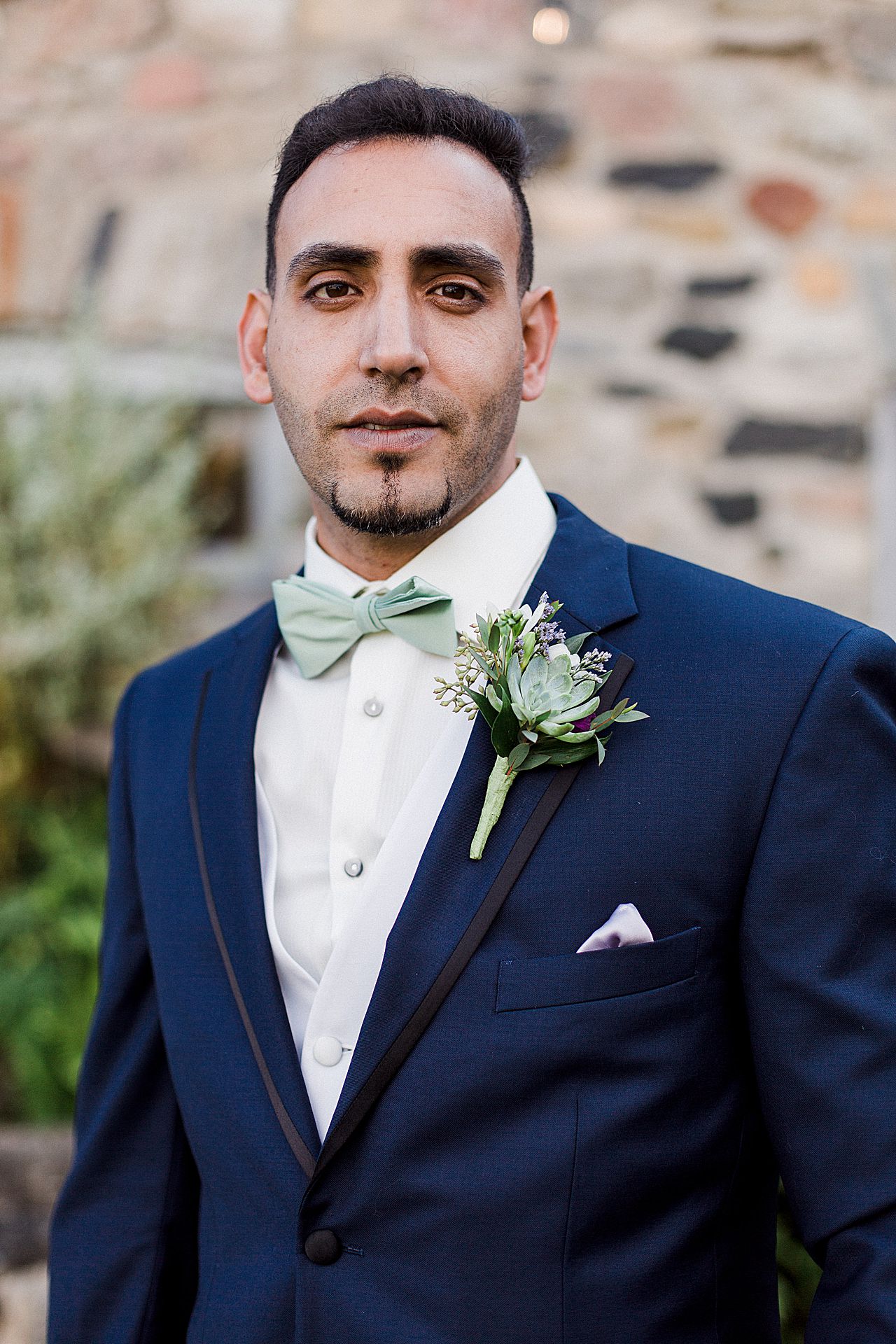 This is a photo of a groom in a blue suit and green bowtie at Castle Farms
