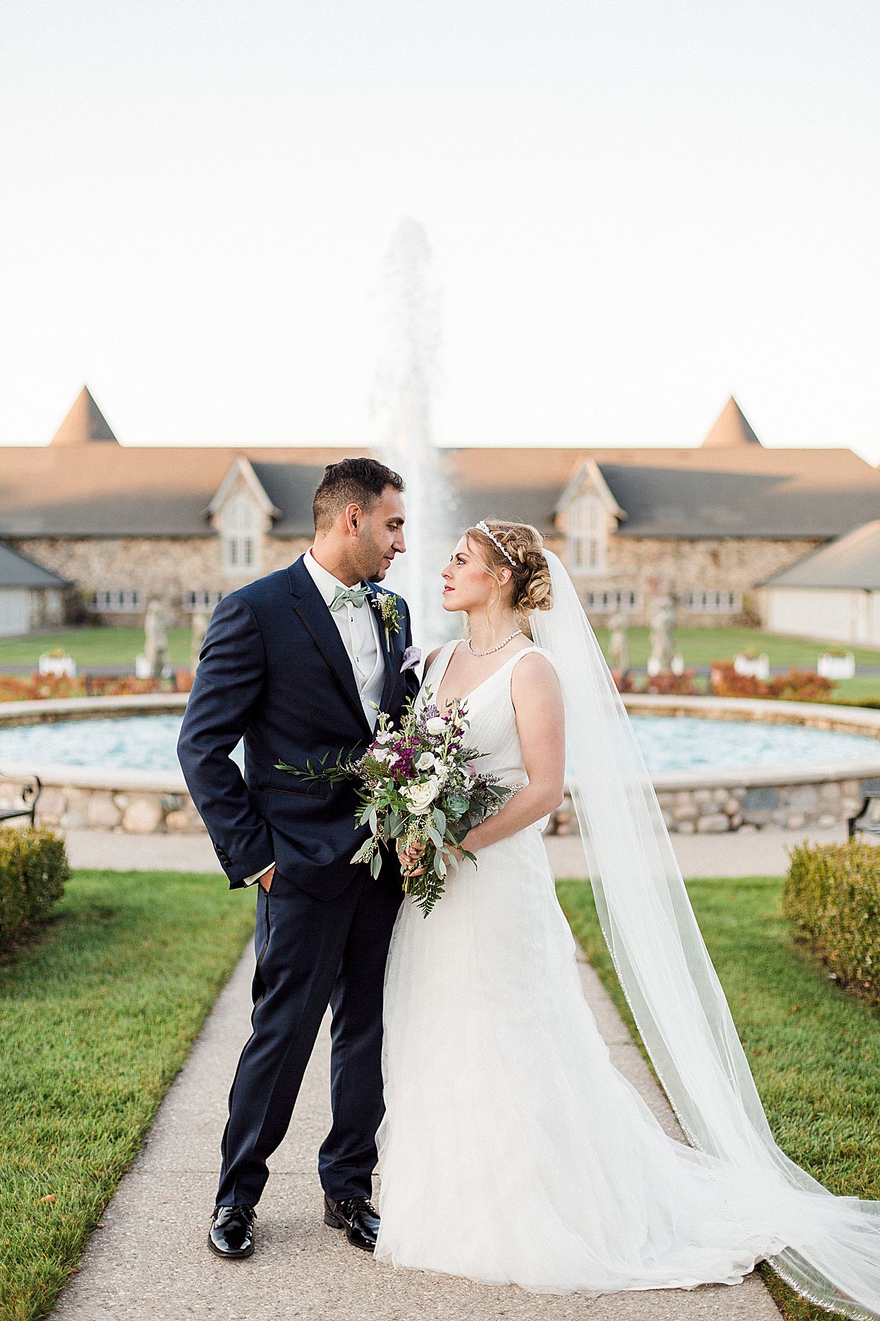 Bride and groom smiling while taking portraits in the Kings Grand Courtyard in Charlevoix, Michigan