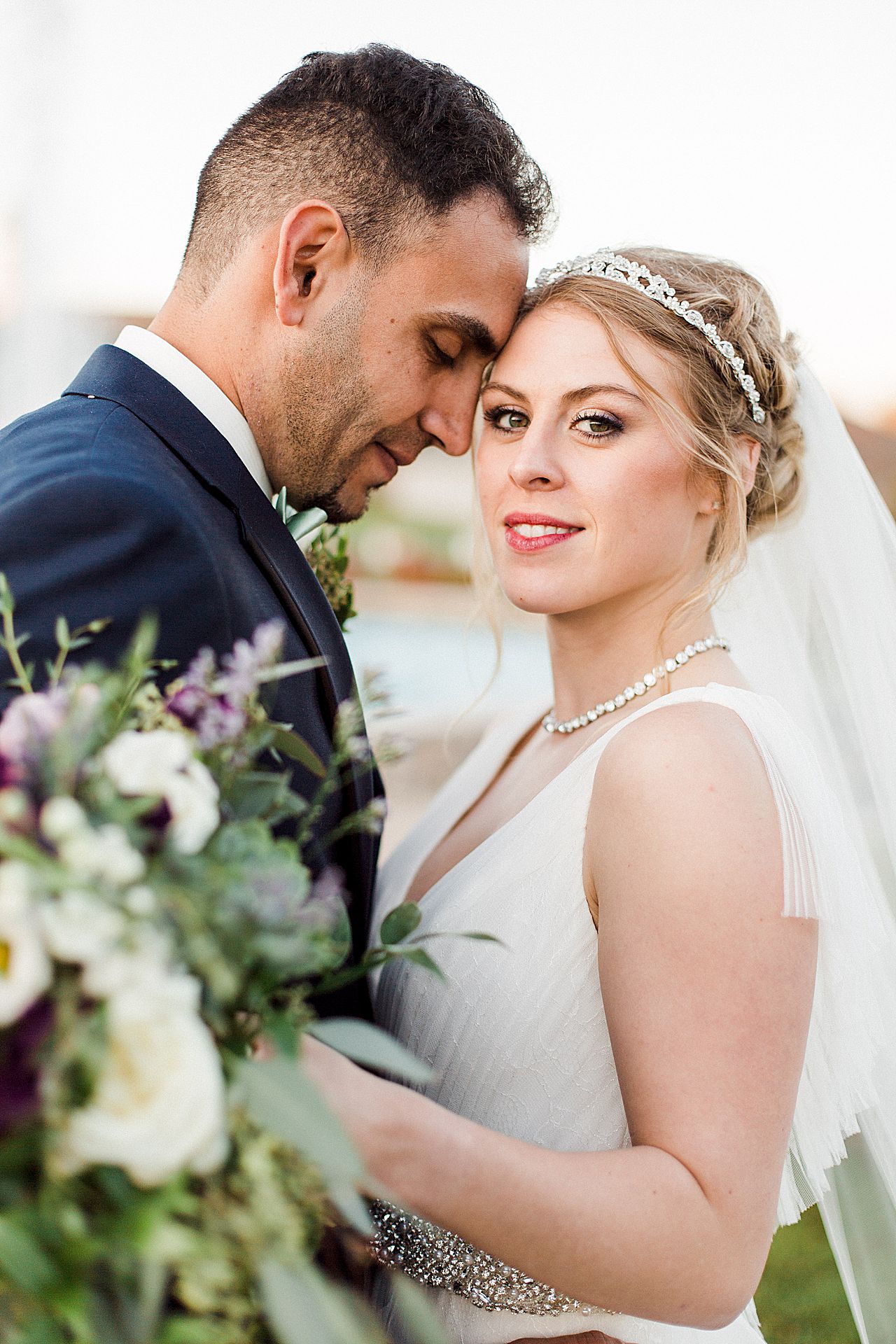 Bride and groom smiling while taking portraits in the Kings Grand Courtyard at Castle Farms in Charlevoix, Michigan with a fountain in the background