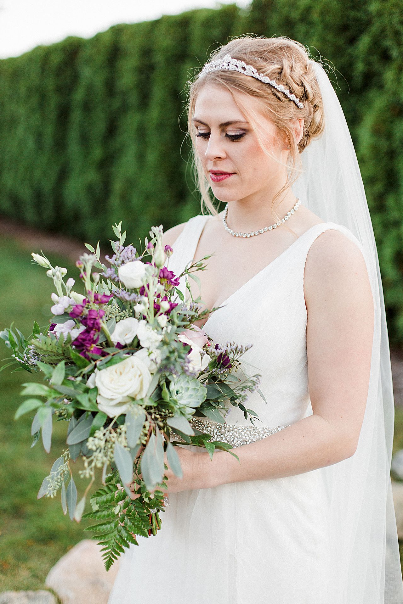 The bride looking at her bouquet in Butterfly Garden at Castle Farms in Charlevoix, Michigan