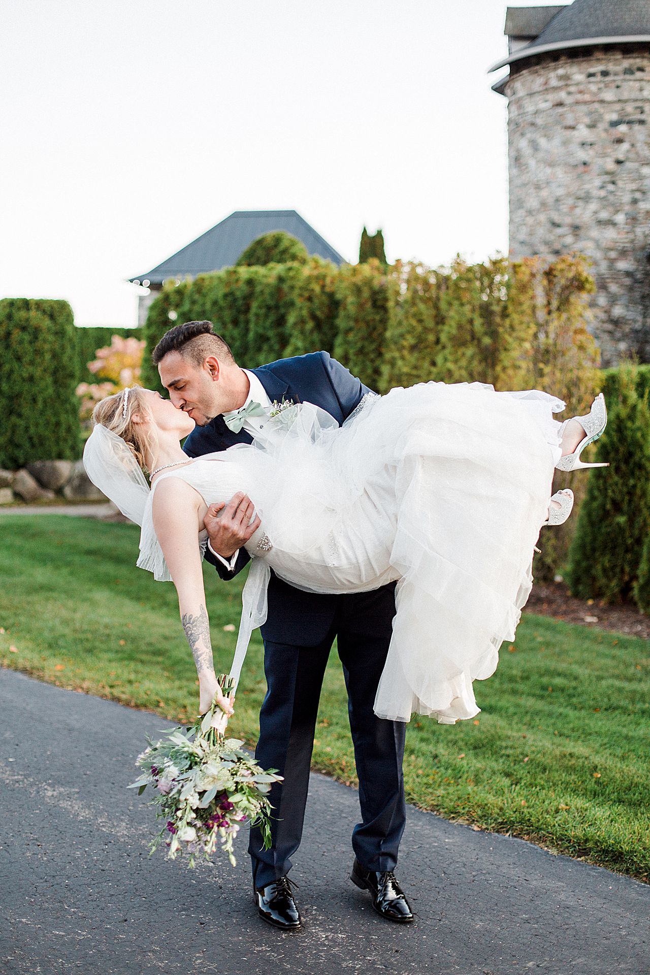 The groom picking up the bride and kissing her with Castle Farms in the background