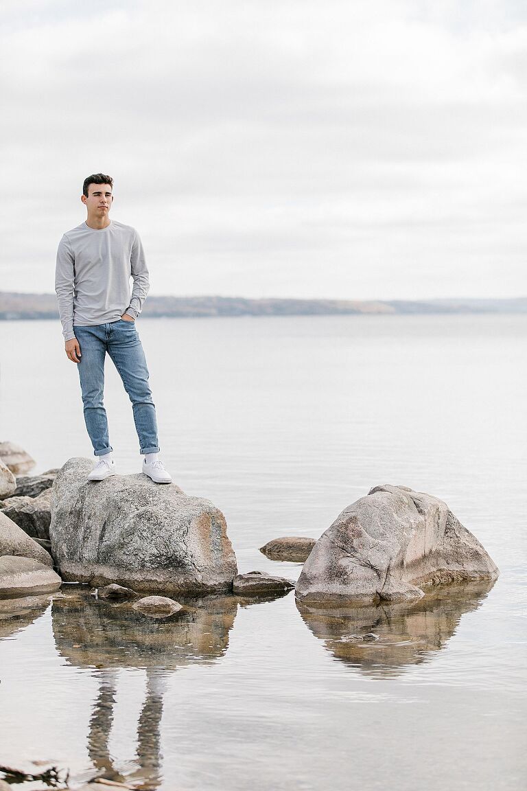 Senior standing on rocks near Round Lake in Charlevoix, Michigan